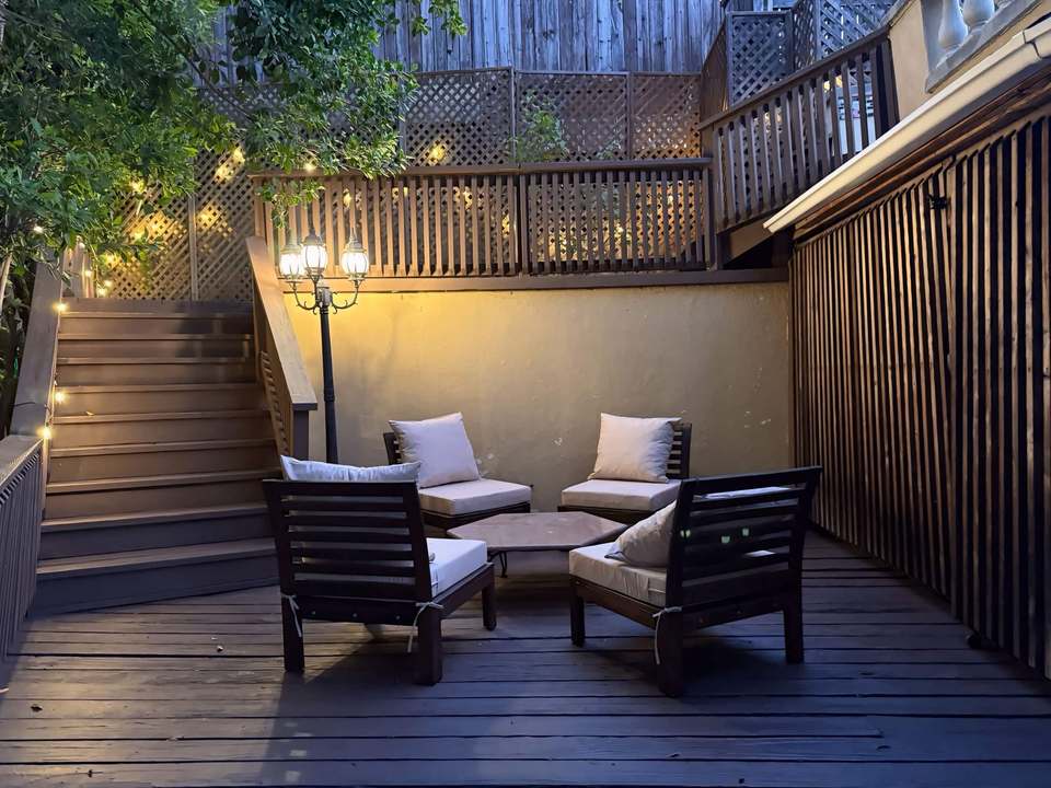 Mid-level teak lounge nook with string lights on the deck path to the rooftop