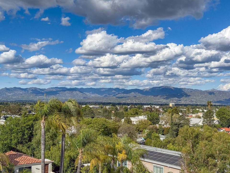 Wide view over the San Fernando Valley to the mountains under a cloudy blue sky