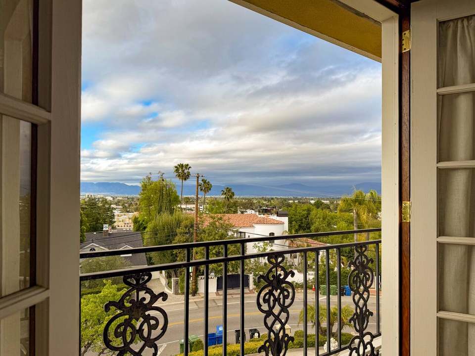 Juliet balcony framing a view over rooftops and palms to the Valley