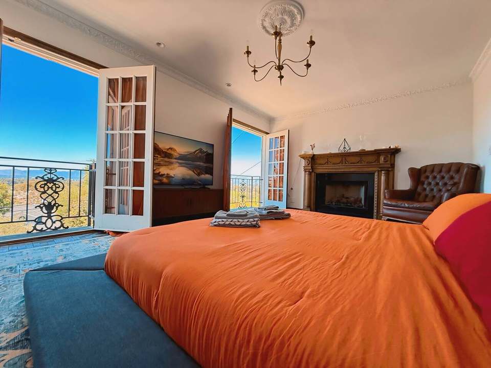Primary bedroom with a low king bed, fireplace and French doors open to Valley views