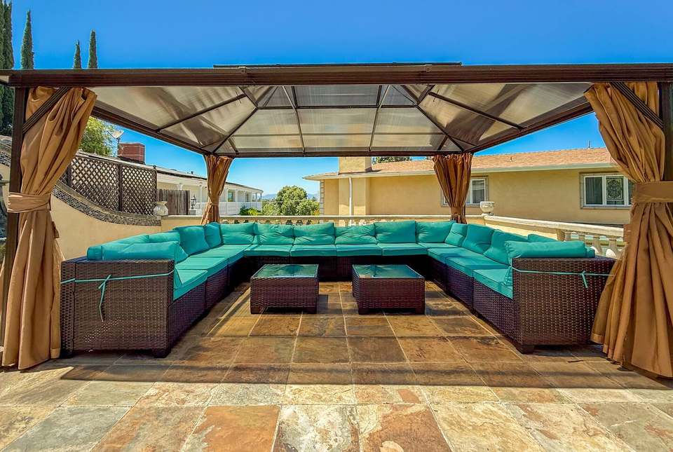 Rooftop gazebo with a wraparound turquoise sectional and gold curtains