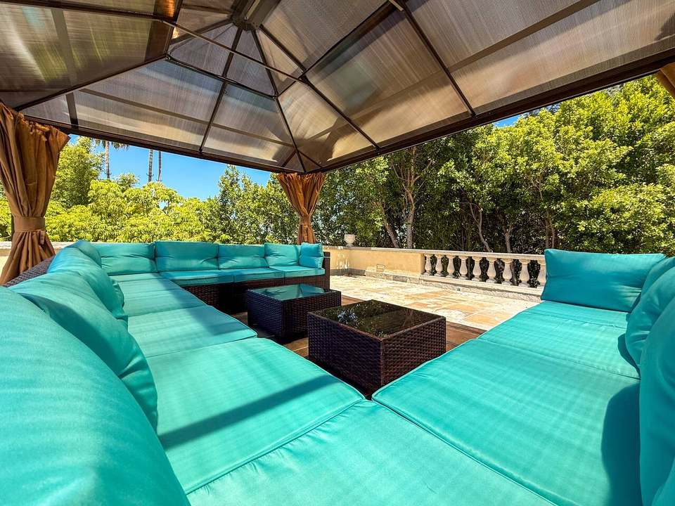 Inside the rooftop gazebo lounge, a wraparound sectional surrounded by greenery
