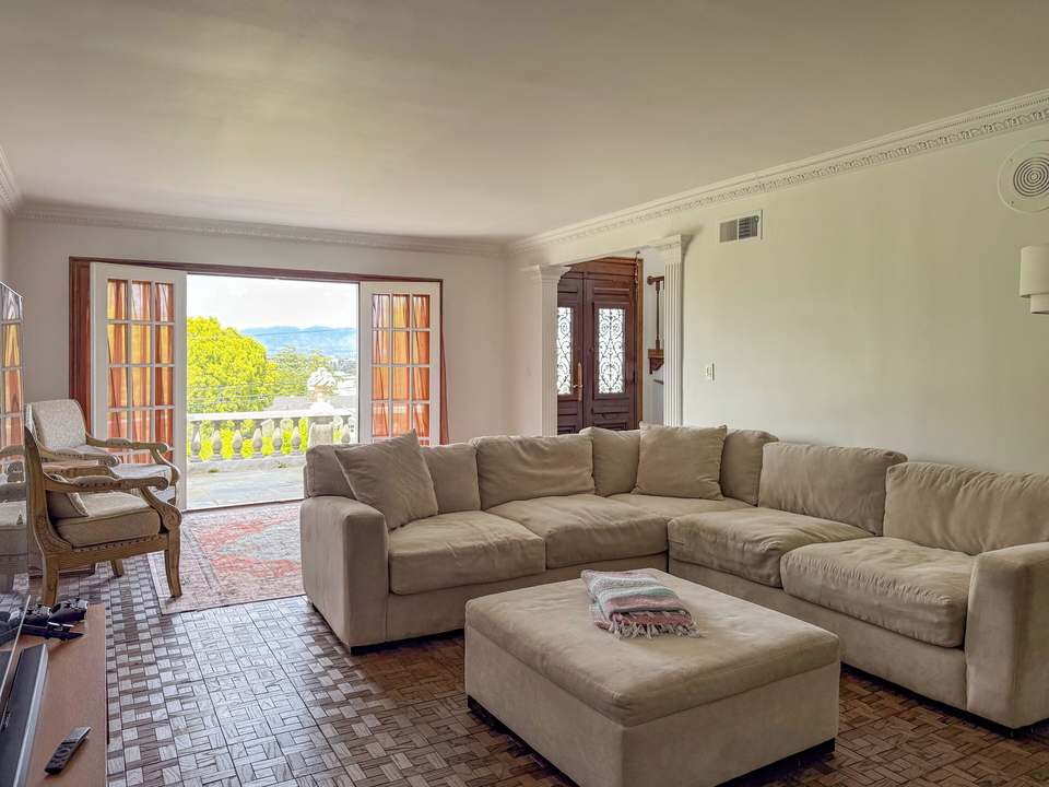 Living room with a beige sectional and French doors open to a Valley view