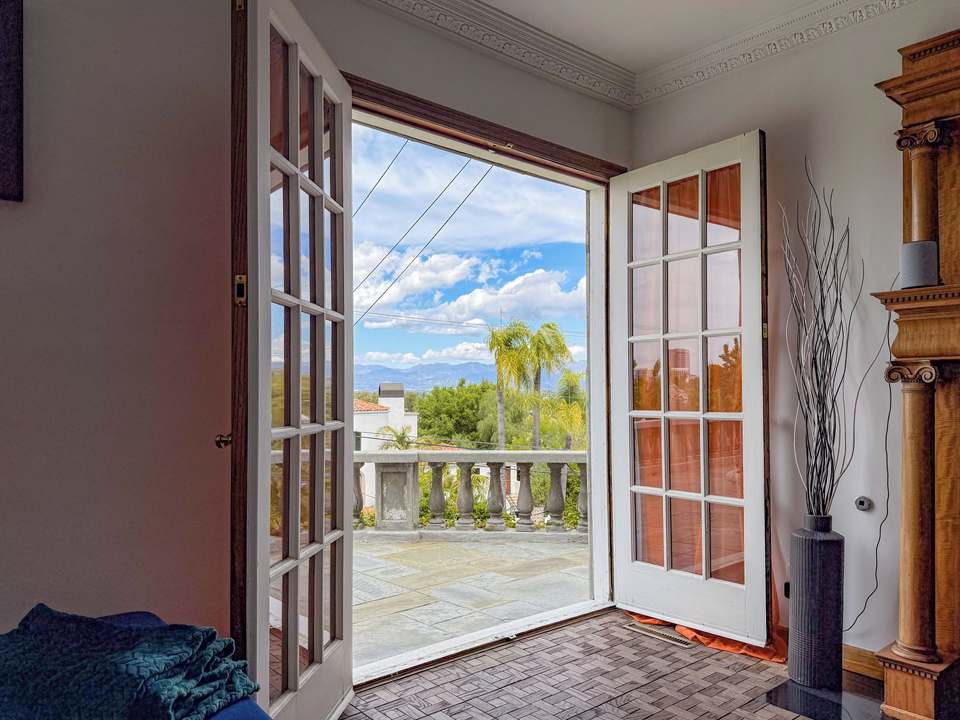French doors from the family room open to the stone terrace and palm trees