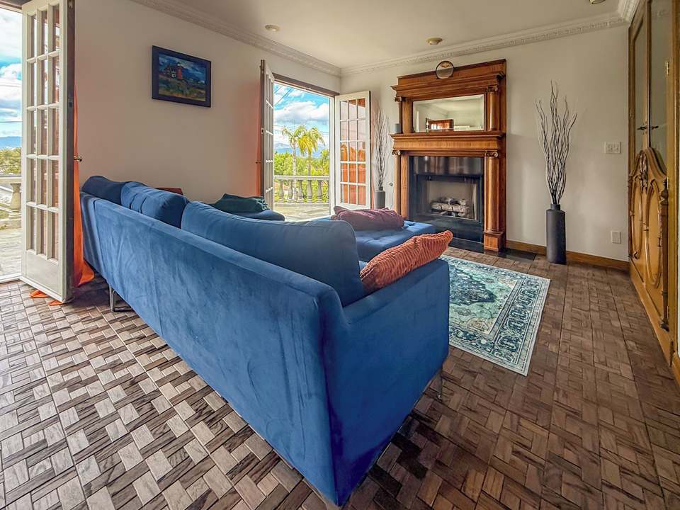 Family room with a blue velvet sectional, carved fireplace and French doors